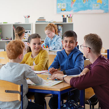 Child wearing Opn play hearing aids raising hand in classroom